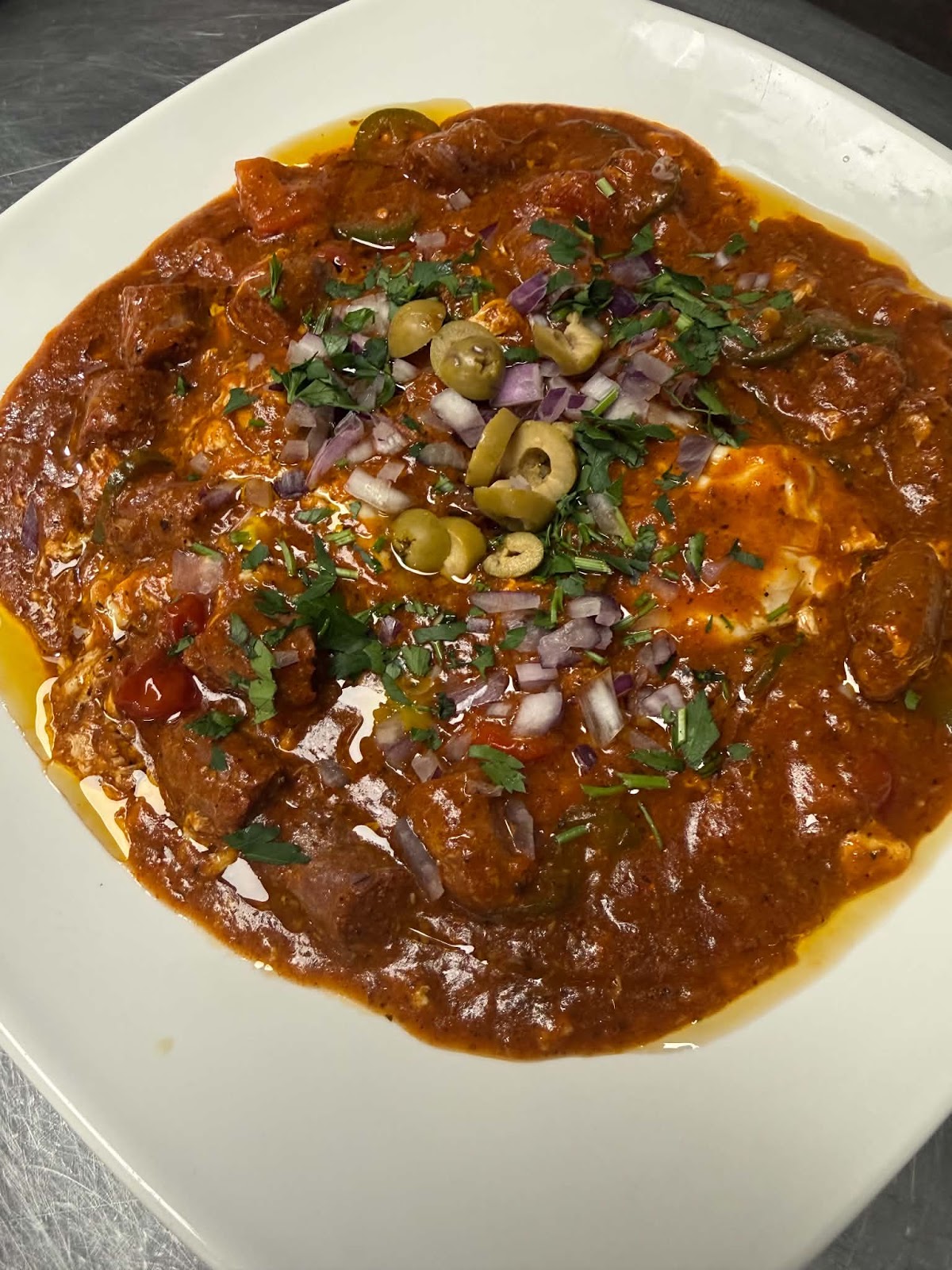 Ojja tunisienne, sauce tomate épicée, œuf, olives et oignons rouges
